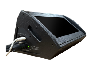 Wedge-shaped stage monitor speaker with cables plugged into the back panel and a green power LED